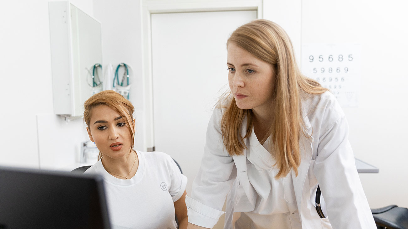 En sjuksköterska och en läkare tittar på en dator.