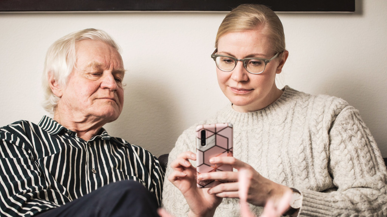 En gammal man och en kvinna på en mobiltelefon.