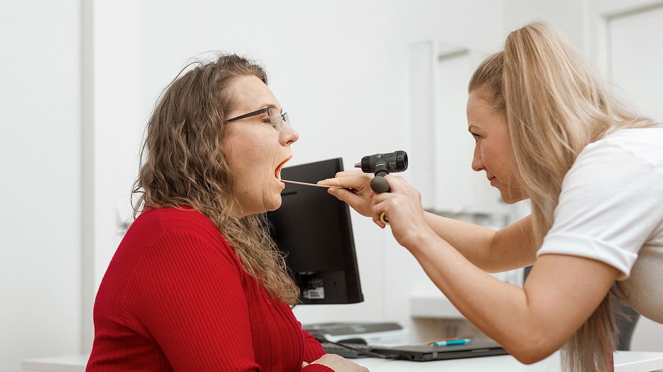 The nurse looks at the patient's throat.