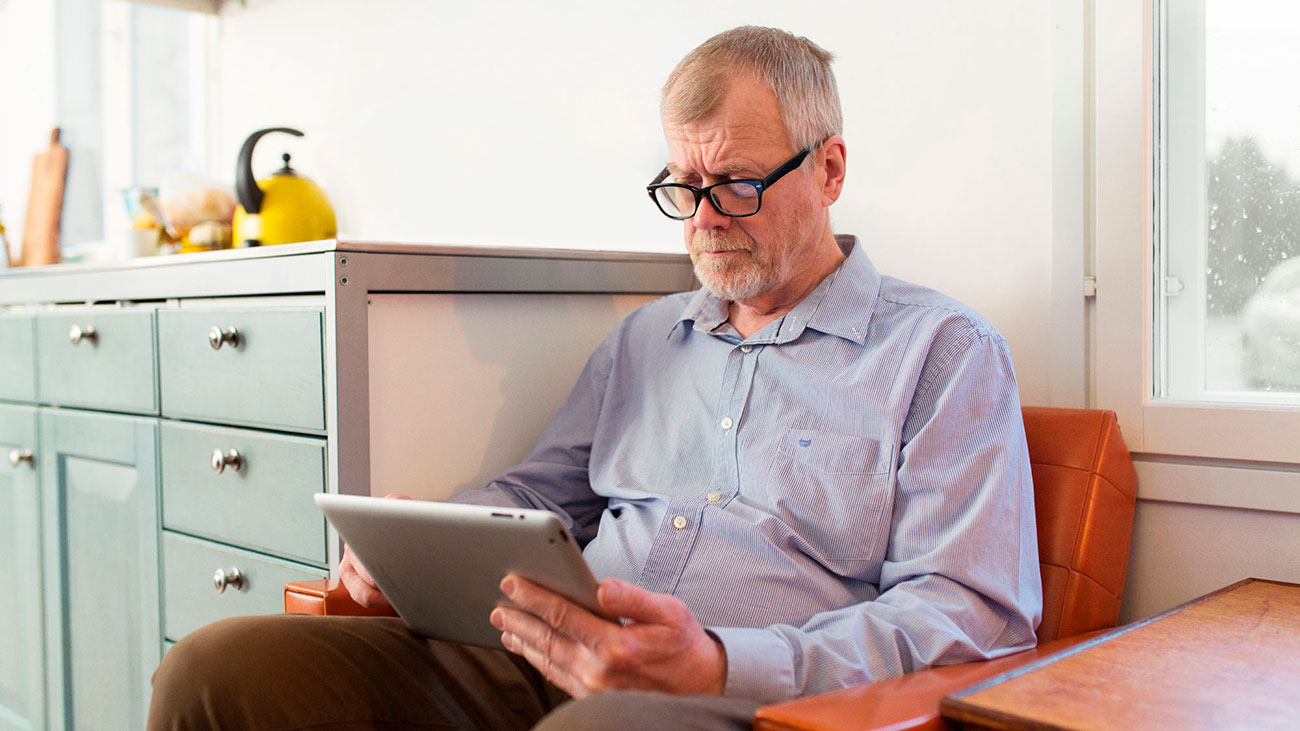 An old man is using his iPad.