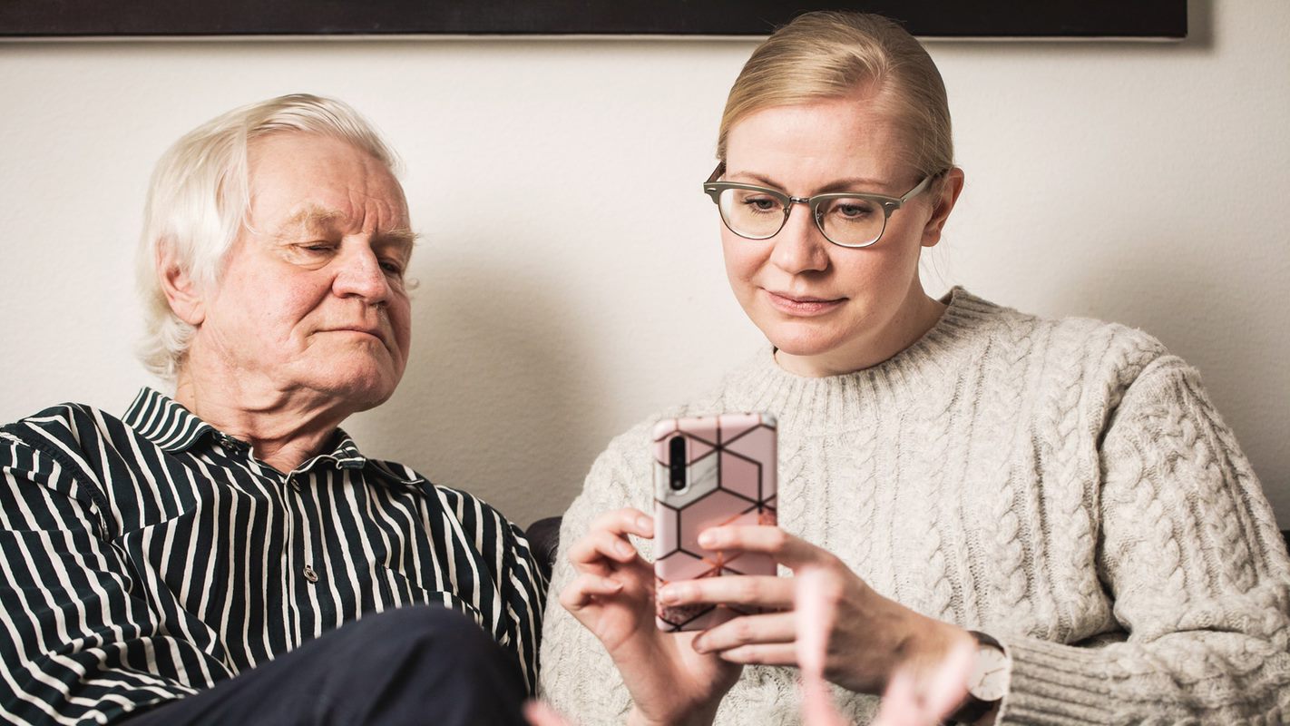 Man ock kvinna sitter och tittar på telefon tillsammans