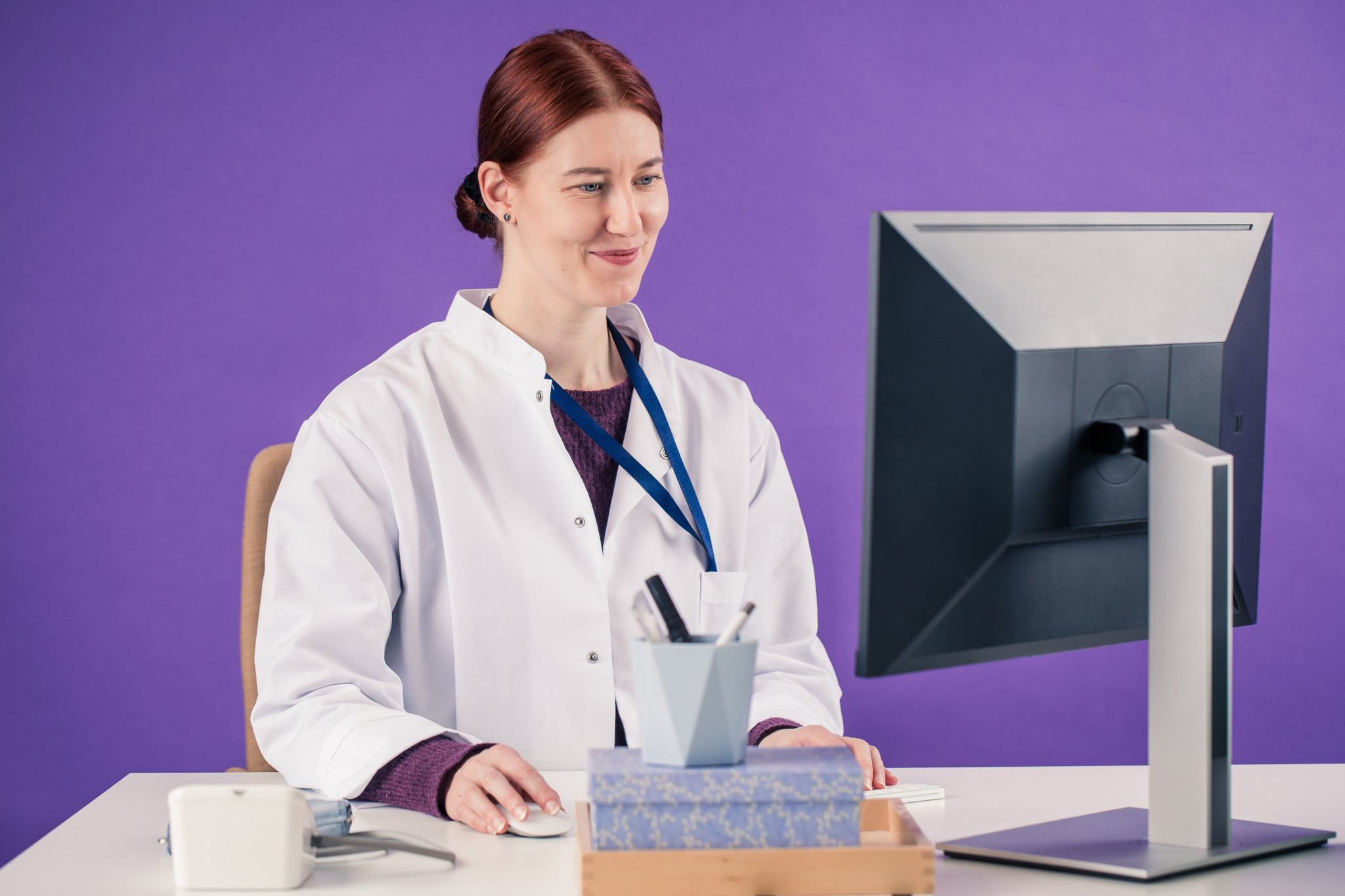 Lääkäri istuu tietokoneen ääressä.