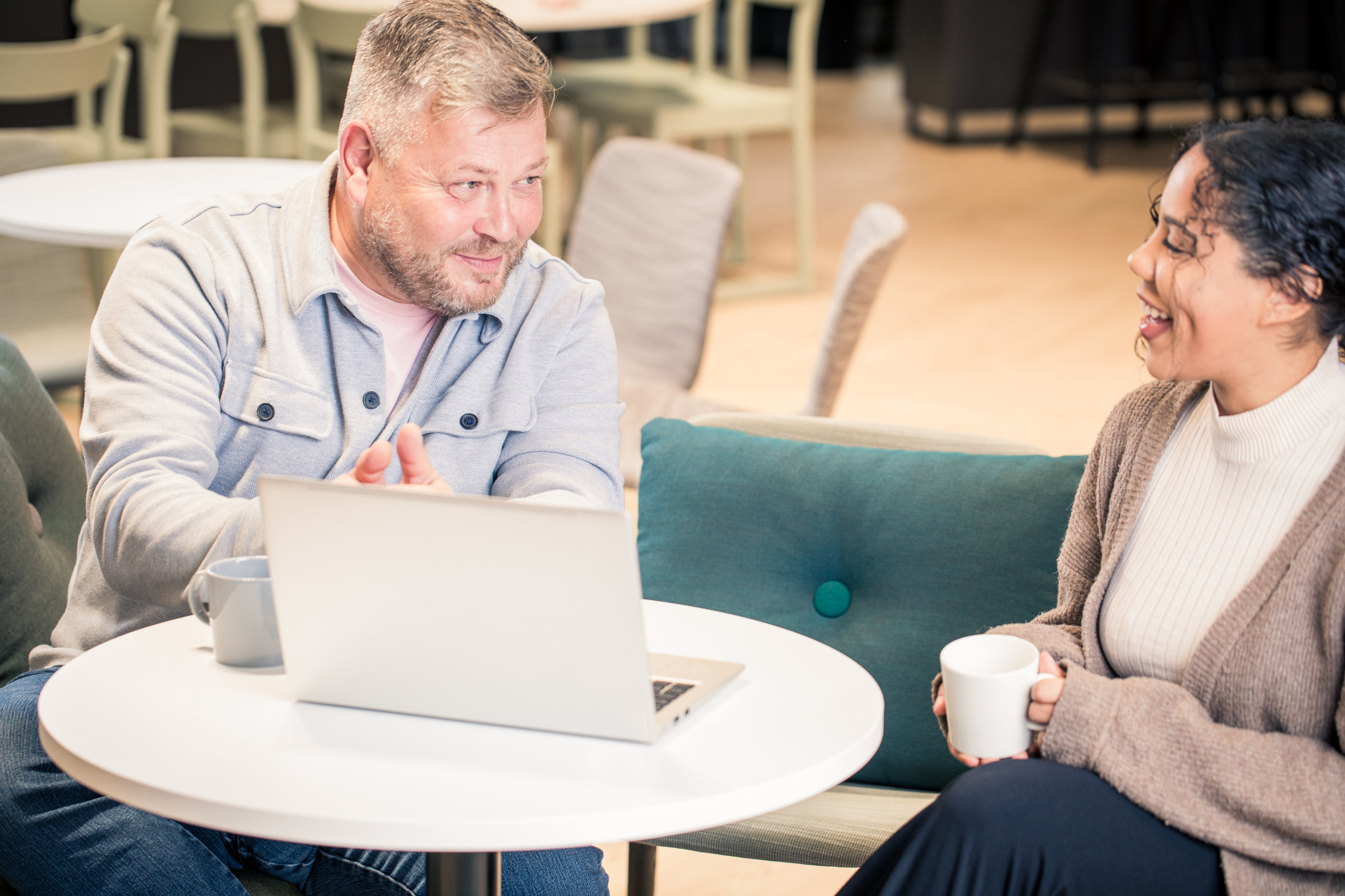 Kaksi järjestelmäkehittäjää istuu ja keskustelee kannettavan tietokoneen äärellä.