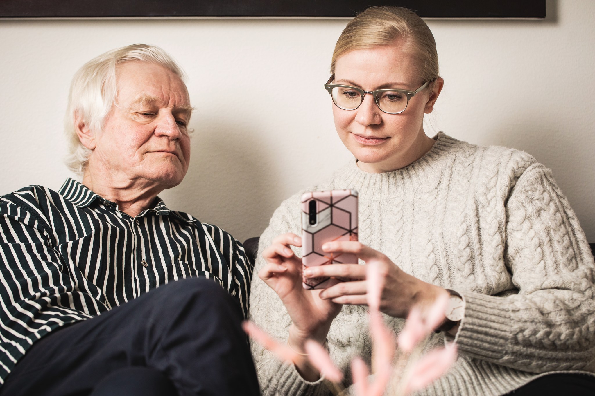 Två personer tittar på en mobiltelefon tillsammans.