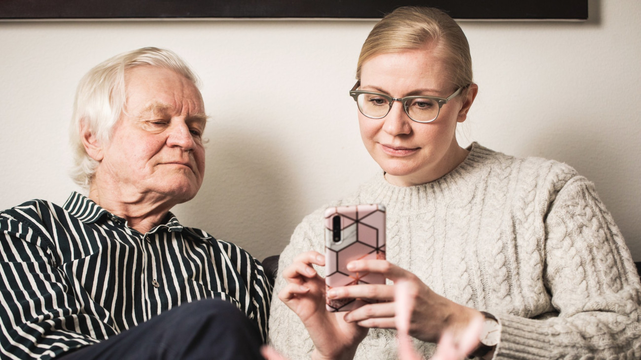 Dottern visar telefonen för sin pappa.