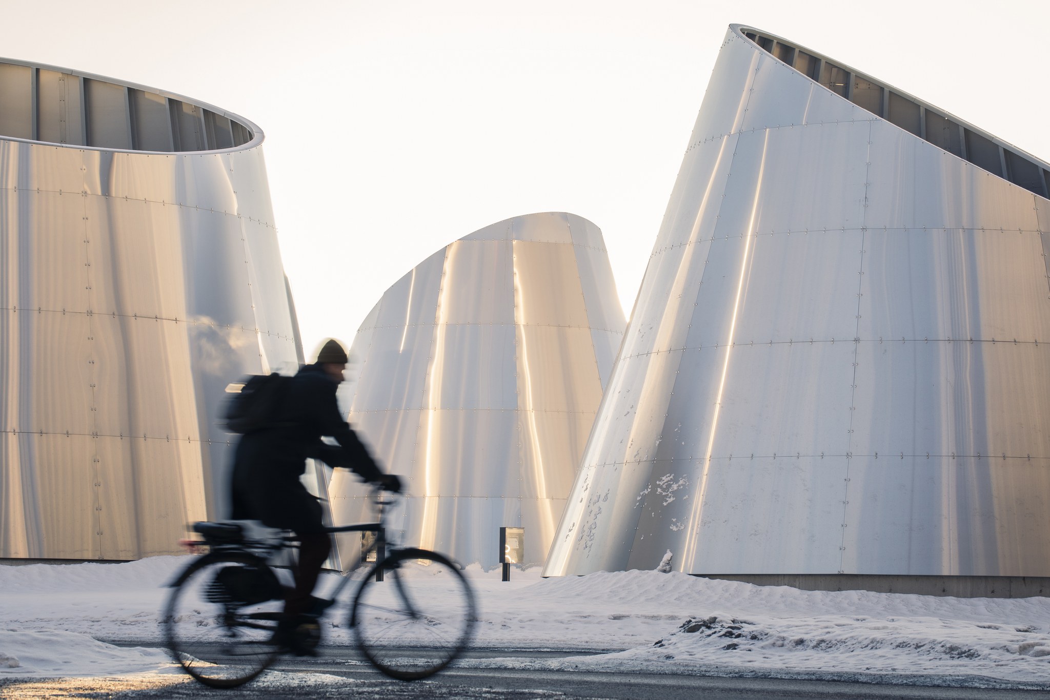 Kuvassa pyöräilee henkilö modernien rakennusten välissä.